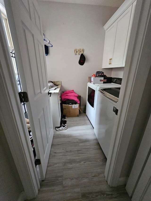 laundry area with cabinets, independent washer and dryer, and light hardwood / wood-style floors