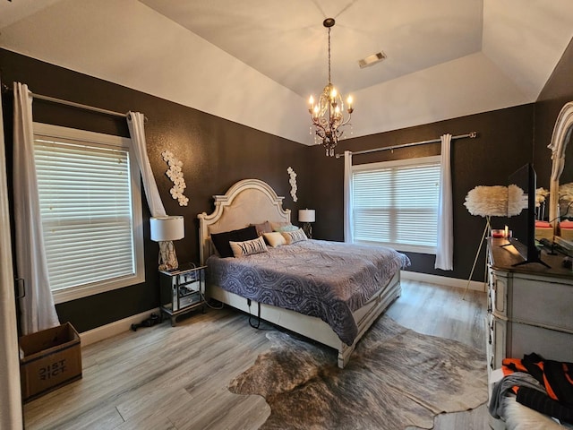 bedroom featuring a chandelier, lofted ceiling, and hardwood / wood-style flooring