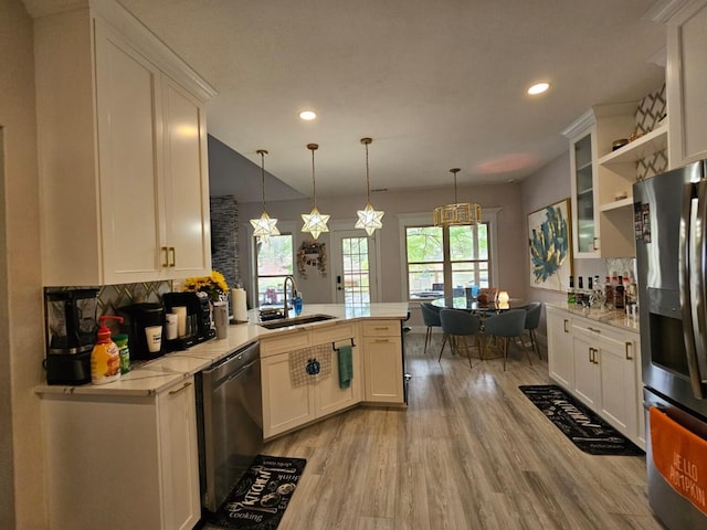 kitchen with stainless steel appliances, kitchen peninsula, white cabinetry, and hanging light fixtures