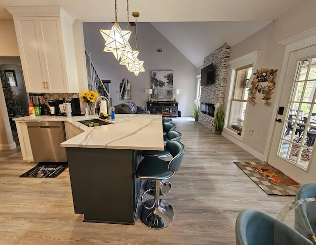 kitchen with kitchen peninsula, light wood-type flooring, sink, pendant lighting, and dishwasher