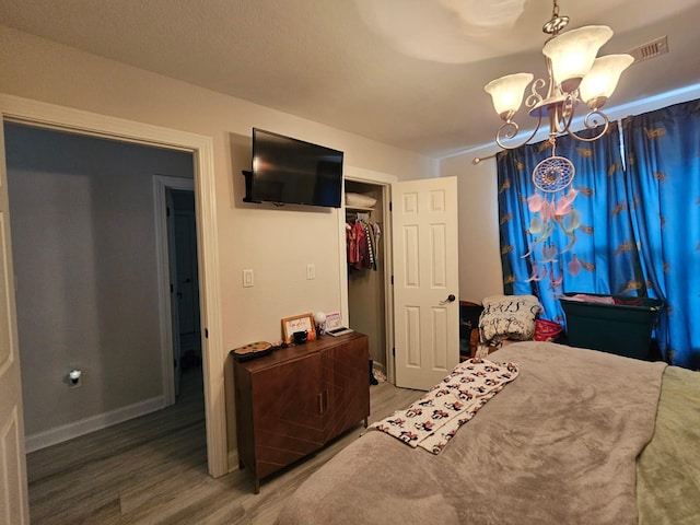 bedroom with a notable chandelier, wood-type flooring, and a closet