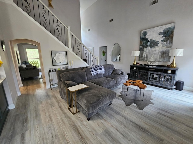 living room featuring light wood-type flooring and a towering ceiling