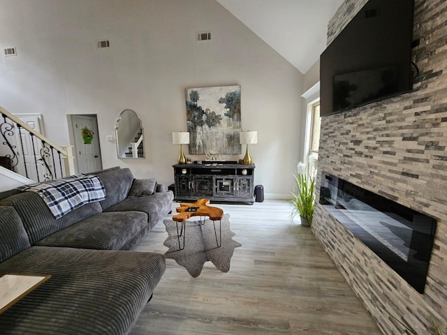 living room with high vaulted ceiling and light wood-type flooring