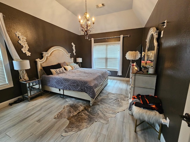 bedroom with hardwood / wood-style floors, vaulted ceiling, and a notable chandelier