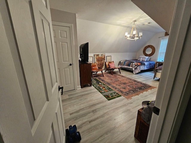 bedroom with a chandelier, light hardwood / wood-style floors, and vaulted ceiling