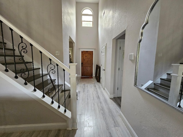 foyer entrance with a towering ceiling and light hardwood / wood-style floors