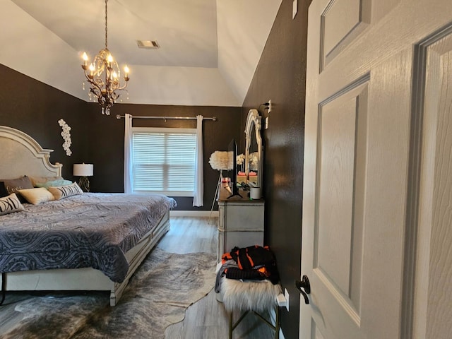 bedroom with hardwood / wood-style flooring, lofted ceiling, and a notable chandelier