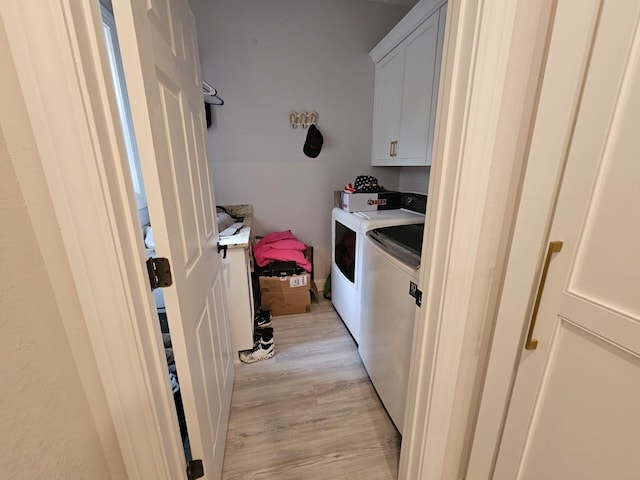 clothes washing area with light hardwood / wood-style floors, cabinets, and washing machine and clothes dryer