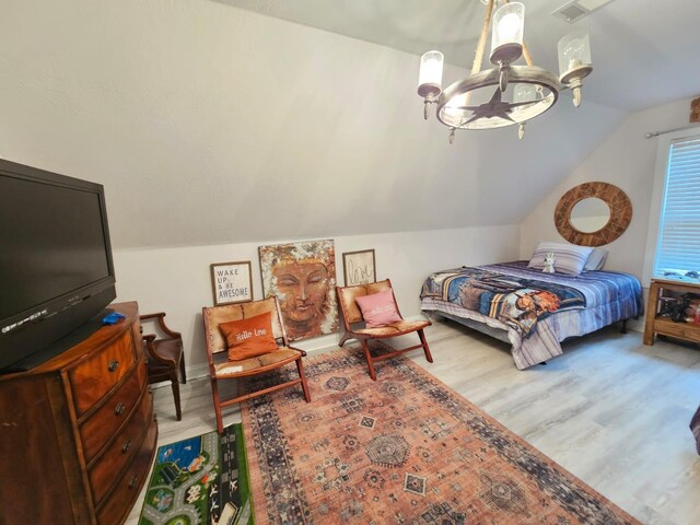 bedroom featuring a notable chandelier, light hardwood / wood-style floors, and lofted ceiling