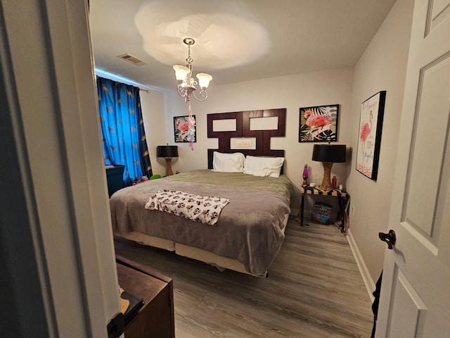 bedroom with dark hardwood / wood-style flooring and a notable chandelier