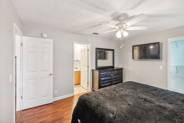 bedroom with a spacious closet, ceiling fan, dark wood-type flooring, ensuite bathroom, and a closet