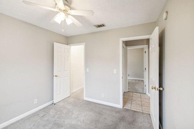 unfurnished bedroom featuring a textured ceiling, ceiling fan, and light carpet