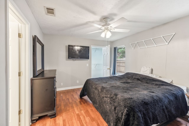 bedroom featuring a textured ceiling, ceiling fan, hardwood / wood-style flooring, a spacious closet, and a closet