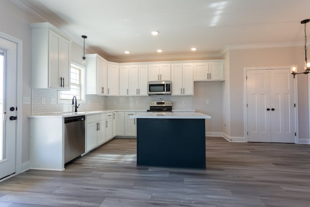 kitchen featuring white cabinets, a center island, stainless steel appliances, and hanging light fixtures