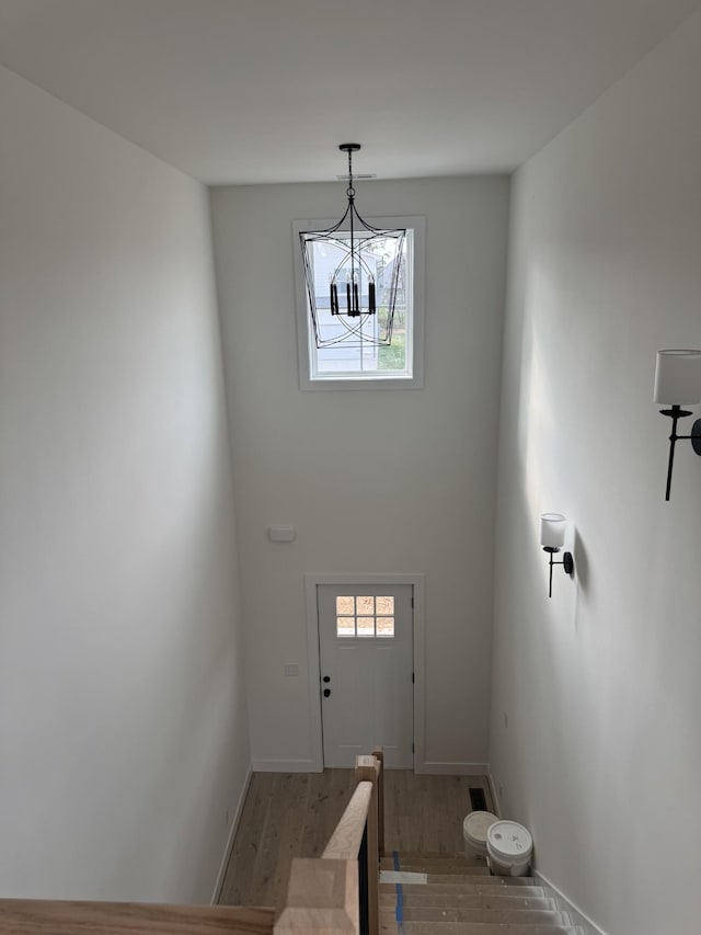 foyer entrance featuring hardwood / wood-style flooring, a wealth of natural light, and an inviting chandelier