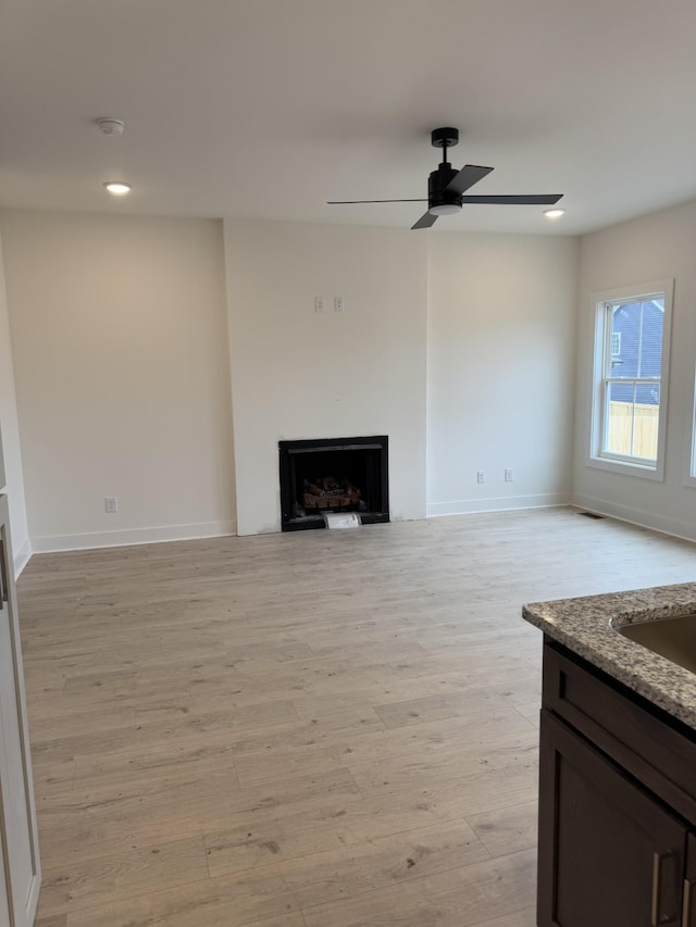 unfurnished living room featuring light hardwood / wood-style floors and ceiling fan