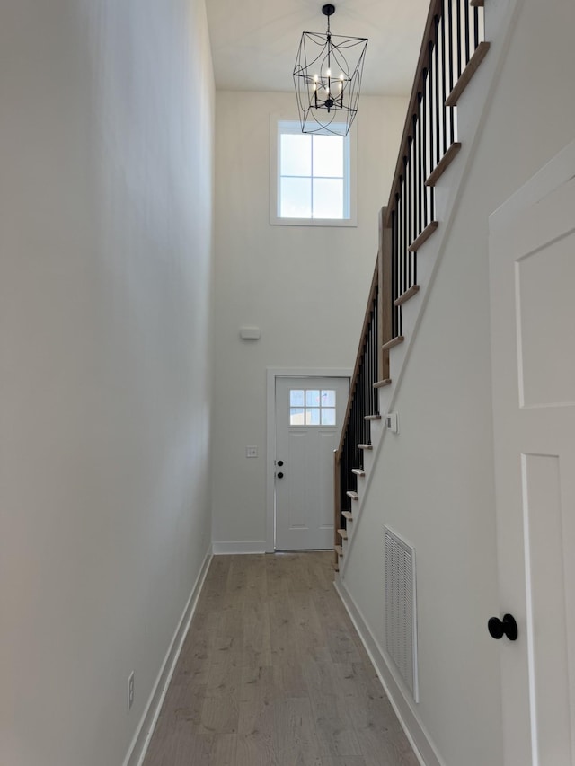 entryway featuring a notable chandelier, light hardwood / wood-style floors, and a high ceiling