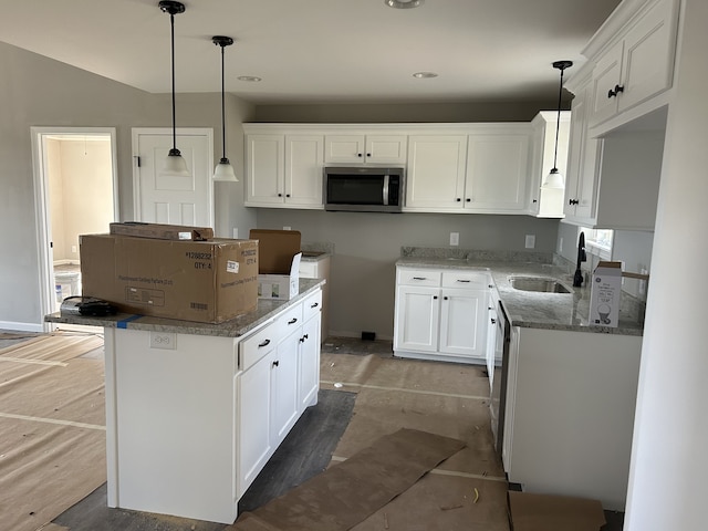 kitchen with sink, stone countertops, appliances with stainless steel finishes, pendant lighting, and white cabinets