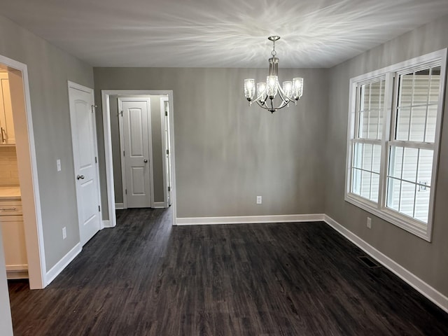 empty room with a chandelier and dark hardwood / wood-style flooring