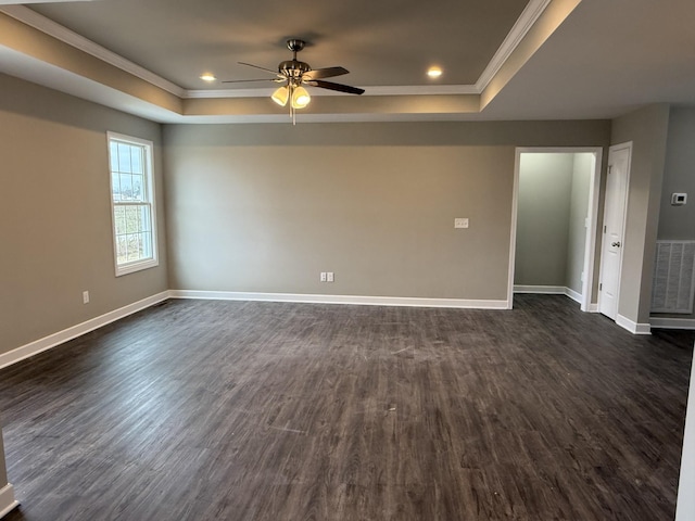 empty room featuring a tray ceiling, ceiling fan, crown molding, and dark hardwood / wood-style floors