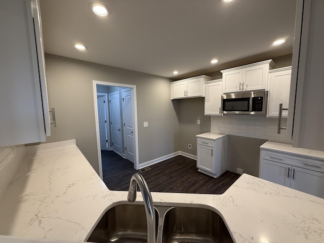 kitchen featuring decorative backsplash, light stone counters, sink, white cabinets, and dark hardwood / wood-style floors