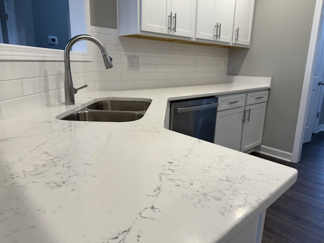 kitchen featuring sink, stainless steel dishwasher, tasteful backsplash, light stone counters, and white cabinetry