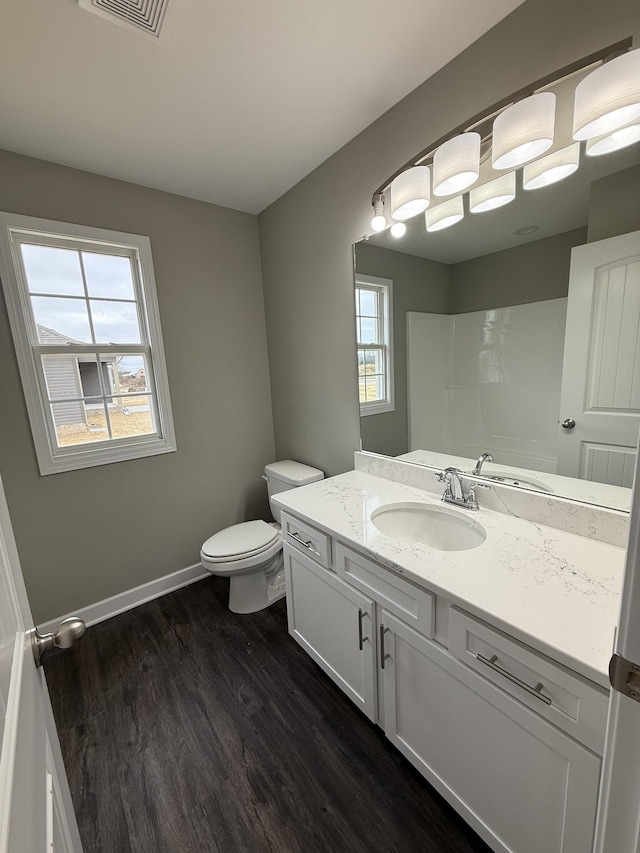 bathroom featuring hardwood / wood-style flooring, vanity, toilet, and a shower