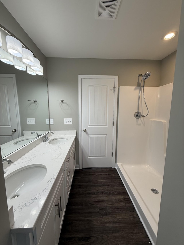 bathroom with a shower, hardwood / wood-style floors, and vanity