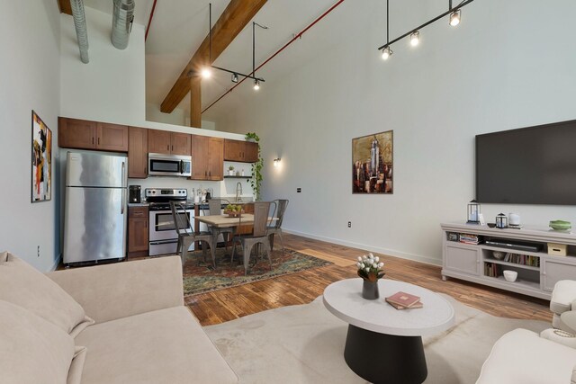 living room featuring high vaulted ceiling, baseboards, and light wood finished floors