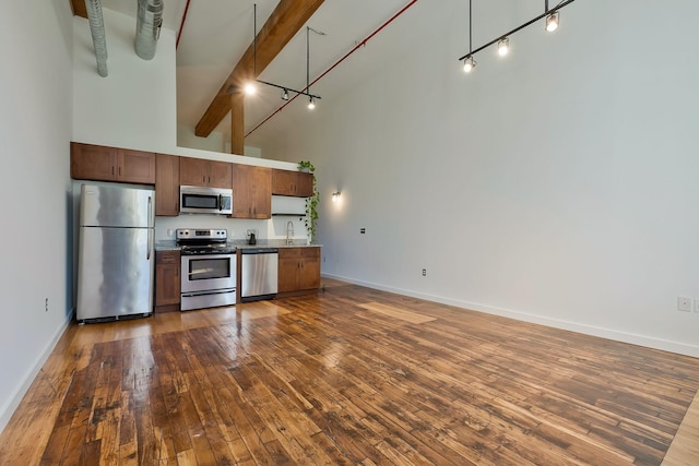 kitchen with appliances with stainless steel finishes, high vaulted ceiling, baseboards, and dark wood-style floors