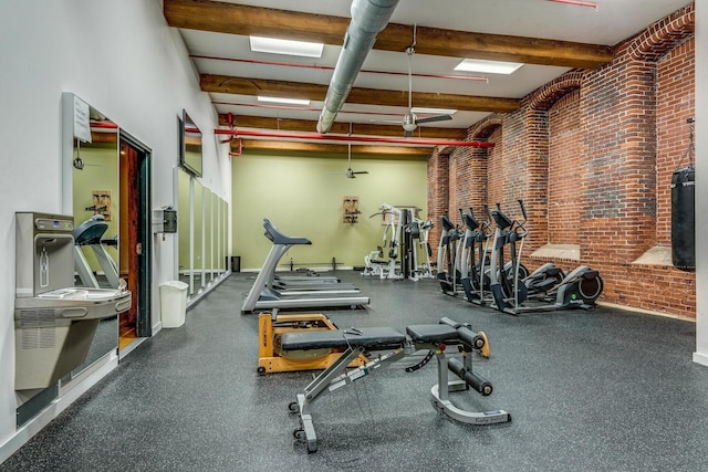 gym featuring brick wall and beam ceiling