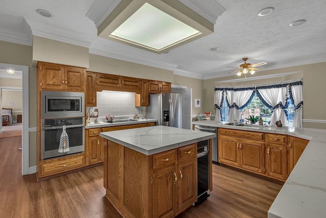 kitchen featuring ceiling fan, a center island, stainless steel appliances, dark hardwood / wood-style floors, and ornamental molding