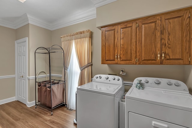 washroom featuring cabinets, ornamental molding, washer and dryer, and light hardwood / wood-style floors