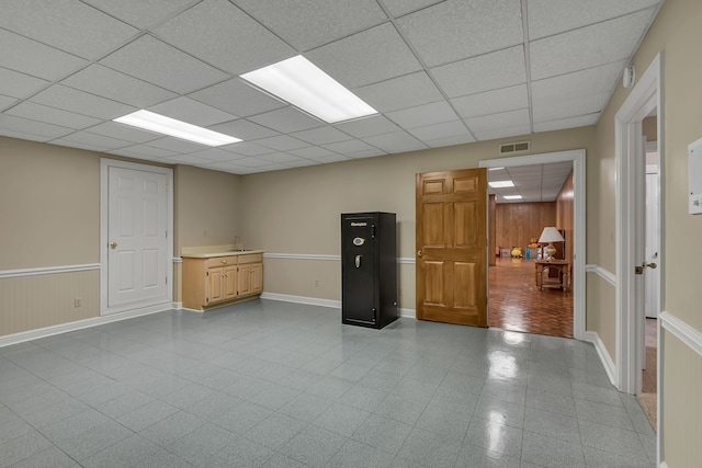 interior space with a paneled ceiling and wooden walls