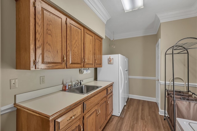 kitchen with white refrigerator, sink, light wood-type flooring, and crown molding