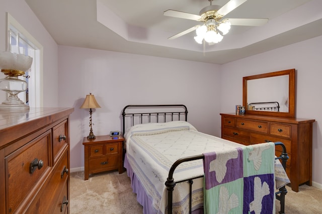 carpeted bedroom with a tray ceiling and ceiling fan