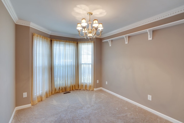 carpeted spare room featuring ornamental molding and a chandelier