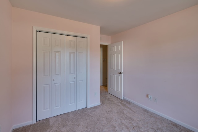 unfurnished bedroom with light colored carpet and a closet