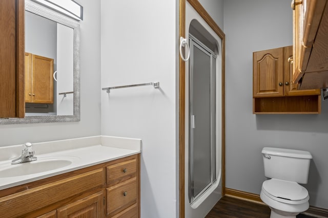 bathroom featuring wood-type flooring, vanity, toilet, and a shower with shower door