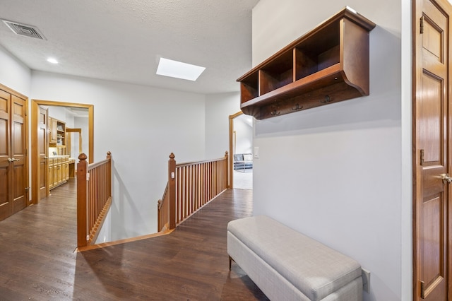 hall with a skylight, dark wood-type flooring, and a textured ceiling