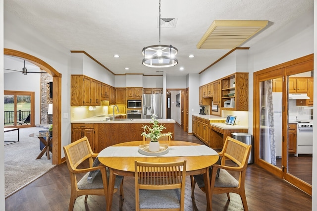 dining area featuring ornamental molding, ceiling fan with notable chandelier, a textured ceiling, dark wood-type flooring, and sink