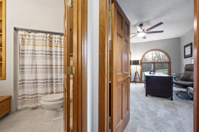 bathroom featuring a shower with curtain, tile patterned flooring, ceiling fan, toilet, and a textured ceiling