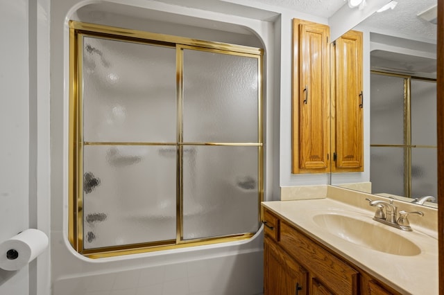 bathroom featuring shower / bath combination with glass door, vanity, and a textured ceiling