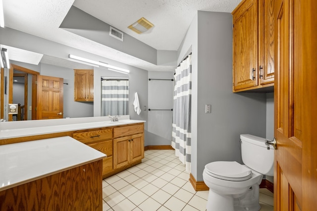 bathroom featuring vanity, a textured ceiling, tile patterned floors, and toilet