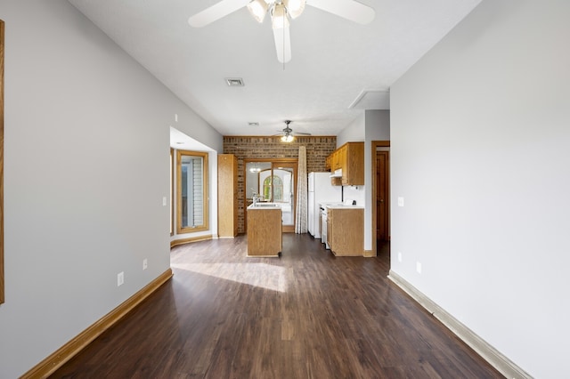 kitchen with dark hardwood / wood-style flooring, white refrigerator, ceiling fan, and brick wall