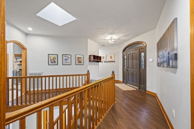 hall featuring dark hardwood / wood-style floors, a textured ceiling, and a skylight