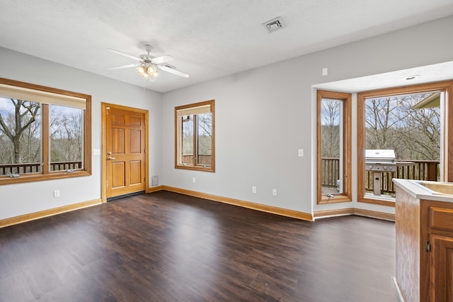 interior space featuring a textured ceiling, a wealth of natural light, dark wood-type flooring, and ceiling fan