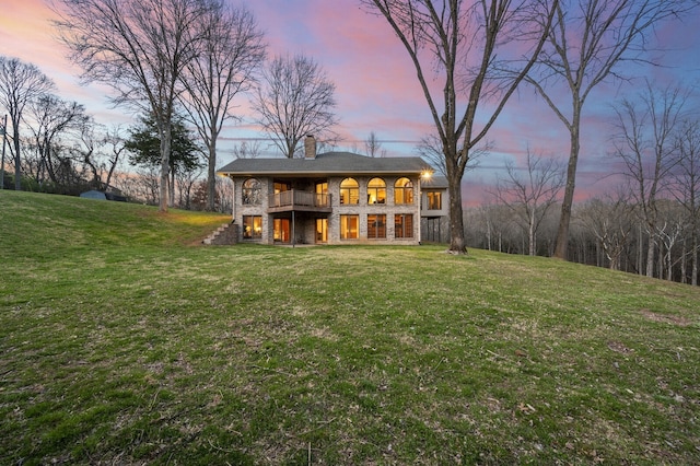 back house at dusk featuring a yard