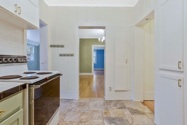 kitchen with decorative backsplash, white range with electric stovetop, tile counters, and crown molding