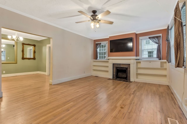 unfurnished living room featuring ceiling fan with notable chandelier, light hardwood / wood-style floors, ornamental molding, and a fireplace